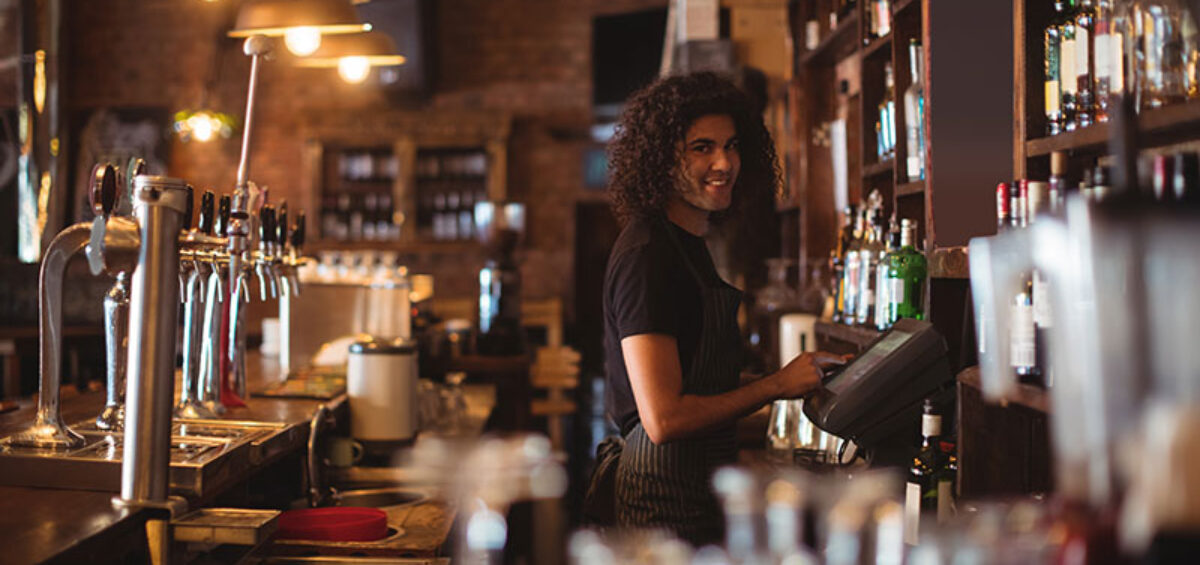 A young bartender behind the bar where Energy Efficiency in Pubs and Clubs is a major concern