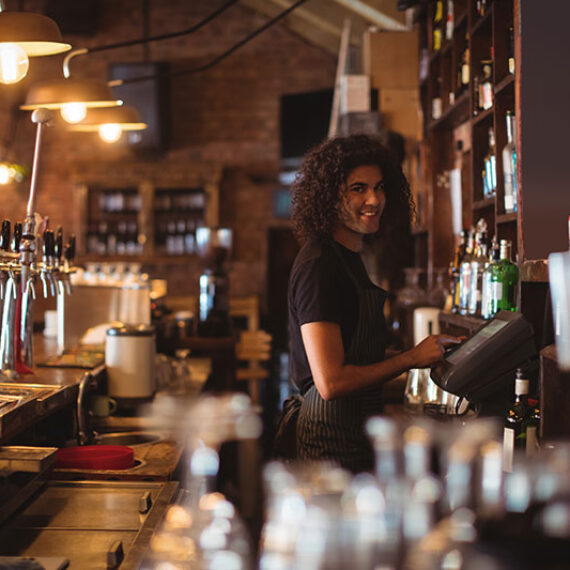 A young bartender behind the bar where Energy Efficiency in Pubs and Clubs is a major concern
