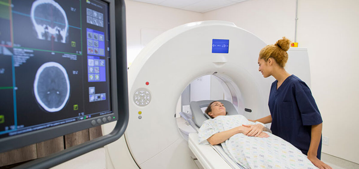 Technician using a CT scanner that requires energy management for medical imaging clinics
