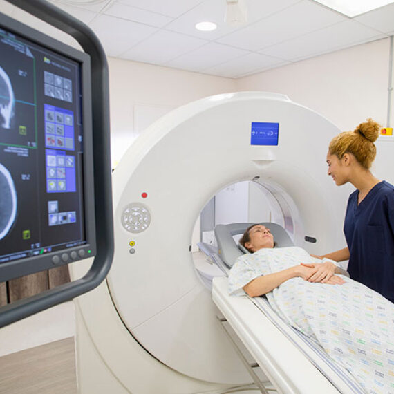 Technician using a CT scanner that requires energy management for medical imaging clinics