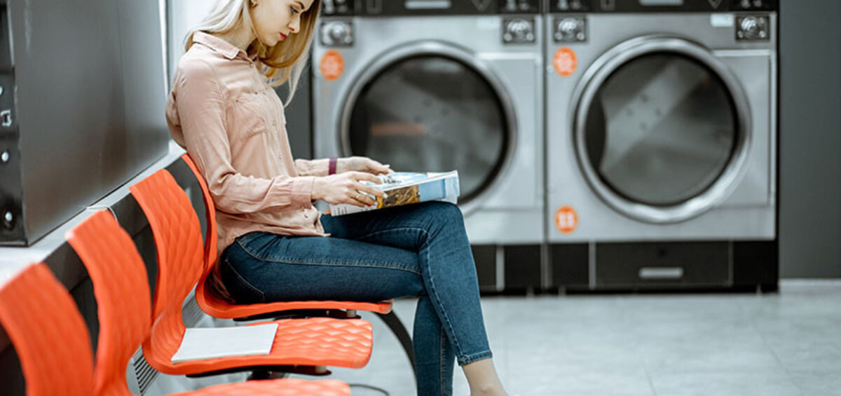 Woman waiting for washing to finish in laundromat where smart energy metering is critical