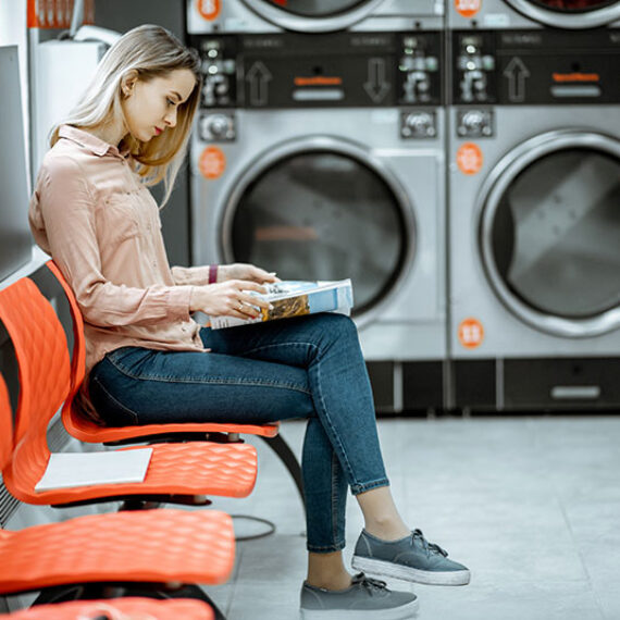 Woman waiting for washing to finish in laundromat where smart energy metering is critical